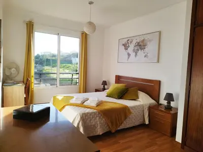 a bedroom with a large bed and a window at MCStylo - Varandas Falésia in Caniço