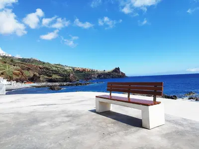 a wooden bench sitting on the beach near the water at MCStylo - Varandas Falésia in Caniço