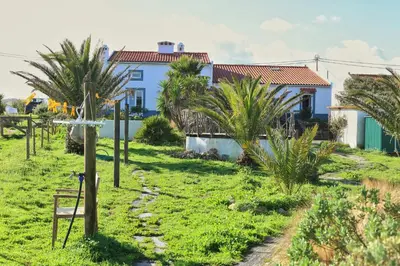 a bedroom with a large bed and a table at Casa Presente Guesthouse in Carrapateira