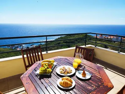 a wooden table with fruit and juice on a balcony at MCStylo-Ocean View in Caniço
