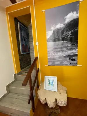a room with a yellow wall with a table and a picture at Casa da Nogueira in Porto Moniz