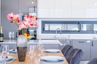 a dining room table with a vase of flowers on it at Villa Plumeria in Arco da Calheta