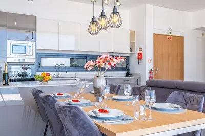 a dining room table with chairs and a vase of flowers at Villa Plumeria in Arco da Calheta