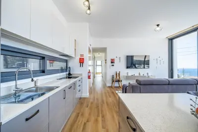 a kitchen with a sink and a living room at Villa Plumeria in Arco da Calheta