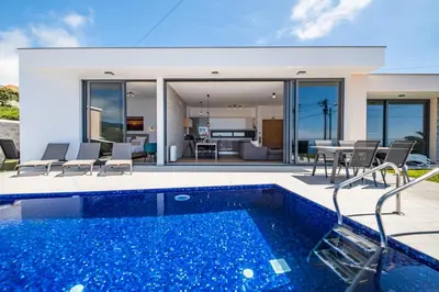a villa with a swimming pool and a house at Villa Plumeria in Arco da Calheta