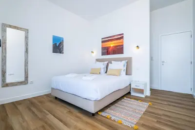 a white bedroom with a bed and a rug at Villa Camelia in Arco da Calheta