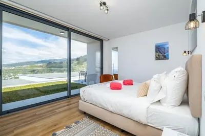 a bedroom with a bed and a large glass window at Villa Camelia in Arco da Calheta