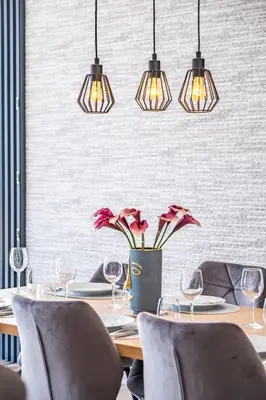 a dining room with a table with chairs and lights at Villa Camelia in Arco da Calheta
