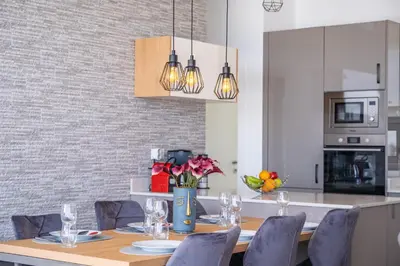 a dining room with a table and chairs and a kitchen at Villa Camelia in Arco da Calheta