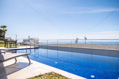 a swimming pool with a view of the beach at Villa Camelia in Arco da Calheta