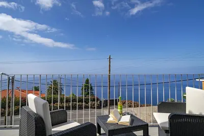 a balcony with chairs and a view of the ocean at Villa Calhetascape by Villa Plus in Estreito da Calheta