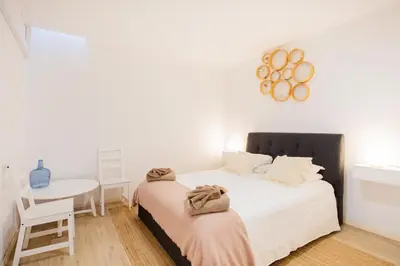 a white bedroom with a bed and a table at Casa Lugos in Funchal