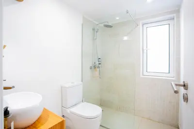 a white bathroom with a toilet and a sink at Casa Lugos in Funchal