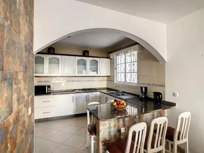 a kitchen with white cabinets and a island with a bowl of fruit at Naya Beach House by LovelyStay in Paul do Mar