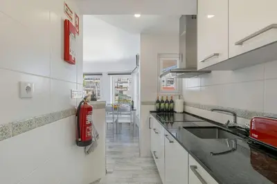 a white kitchen with a fire extinguisher on the wall at Casa Lilas, magnífica vista mar a passos da praia in Luz