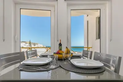 a dining room with a table with a view of the ocean at Casa Lilas, magnífica vista mar a passos da praia in Luz