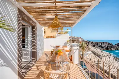 a balcony with a table and chairs and the ocean at Casa da Rocha in Câmara de Lobos