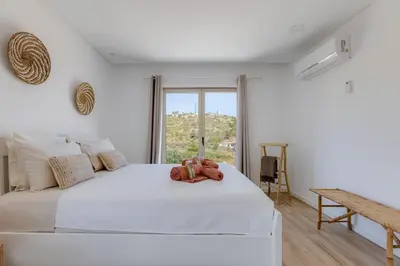 a bedroom with a white bed with a teddy bear on it at Burgau Village and Sea in Burgau
