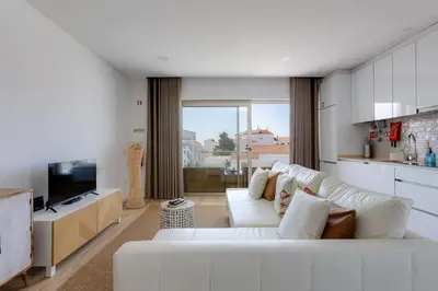 a living room with a white couch and a kitchen at Burgau Village and Sea in Burgau