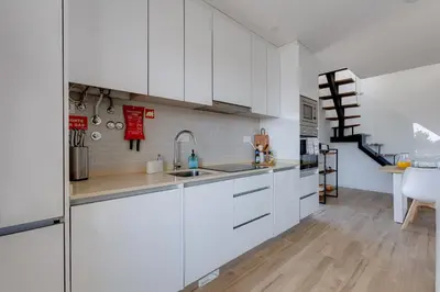 a kitchen with white cabinets and a staircase at Burgau Village and Sea in Burgau