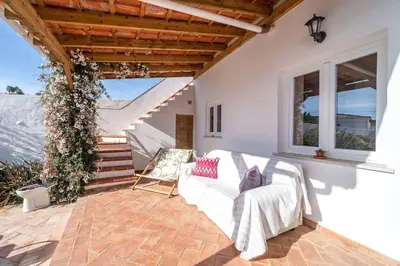 a patio with a white couch and some stairs at Peaceful, spacious & stylish, a real home! in Budens