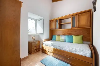 a bedroom with a bed with a wooden headboard and a window at O Refúgio dos Pais in Bordeira