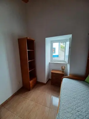 a bedroom with a bed and a dresser and a window at O Refúgio dos Pais in Bordeira