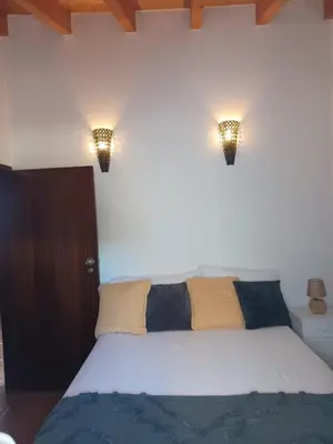 a bedroom with a bed with two lights on the wall at O Refúgio dos Pais in Bordeira