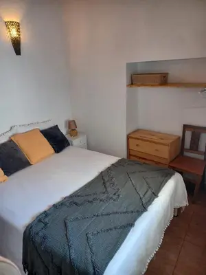a bedroom with a large bed and a night stand at O Refúgio dos Pais in Bordeira