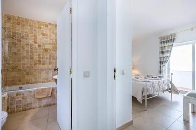 a bathroom with a tub and a bed in a room at CoolHouses Algarve, Luz, 1 bed flat, top floor, a stone's throw to the beach, Casa Isabell in Luz