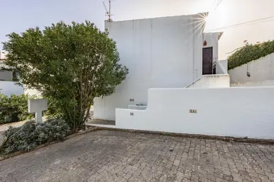 a white house with a tree and a white wall at CoolHouses Algarve, Luz, 1 bed flat, top floor, a stone's throw to the beach, Casa Isabell in Luz