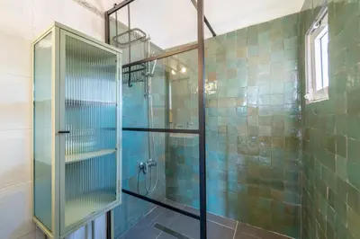 a bathroom with a glass shower with blue tiles at Villa O Altinho Carrapateira in Carrapateira