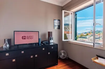 a living room with a tv and a large window at GuestReady - Sao Tiago in Old Town in Funchal
