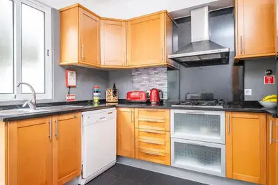 a kitchen with wooden cabinets and white appliances at Home to Stay by Homie in Funchal