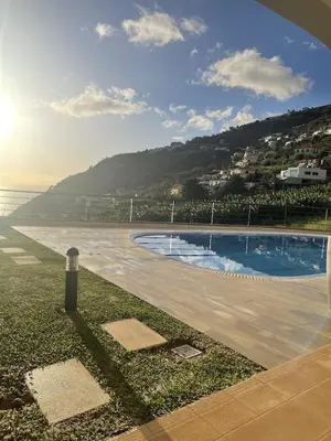 a swimming pool next to a beach with a mountain at Luxury villa with private heated pool, garden and views of the sea and mountains. in Arco da Calheta