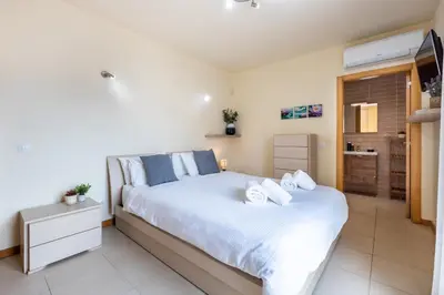 a bedroom with a large bed with white sheets at Burgau Beach House in Burgau