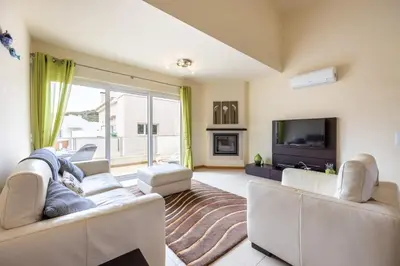 a living room with two couches and a tv at Burgau Beach House in Burgau
