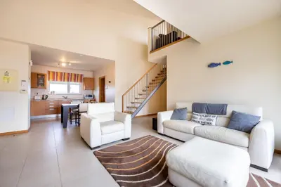 a living room with white furniture and a staircase at Burgau Beach House in Burgau