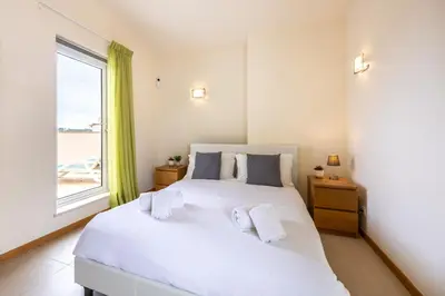 a bedroom with a large white bed with a window at Burgau Beach House in Burgau