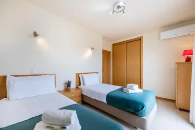 a bedroom with two beds and a blue ottoman at Burgau Beach House in Burgau
