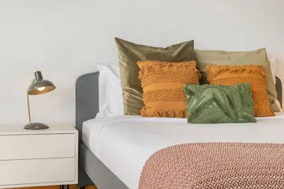 a bed with orange and green pillows and a lamp at Villa Hibiscus by An Island Apart in Calheta