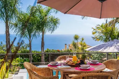 a table with a bowl of fruit and an umbrella at Villa Hibiscus by An Island Apart in Calheta