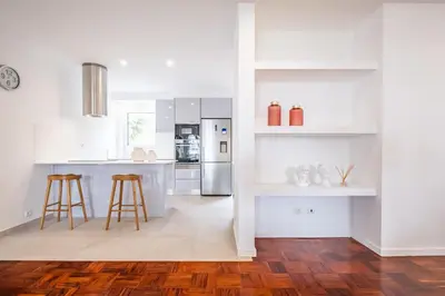 a white kitchen with wooden floors and white cabinets at Recanto da Princesa by Homie in Funchal