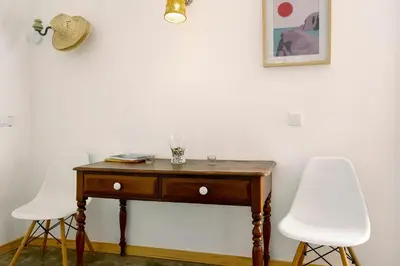a table with two white chairs next to a wall at Calheta Beach House T2 in Calheta