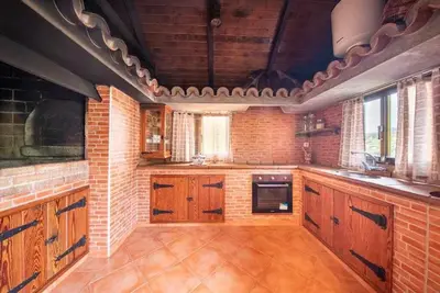 a large kitchen with wooden cabinets and a brick wall at Lombo Cesteiro Guesthouse in Tábua