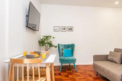 a living room with a table and chairs and a couch at Ribeira do Esmeraldo by Homie in Funchal