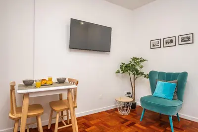 a living room with a table and chairs and a television at Ribeira do Esmeraldo by Homie in Funchal