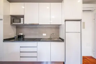 a white kitchen with a sink and a refrigerator at Ribeira do Esmeraldo by Homie in Funchal