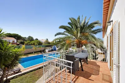 a balcony with a table and a swimming pool at Villa Oliveira in Aljezur