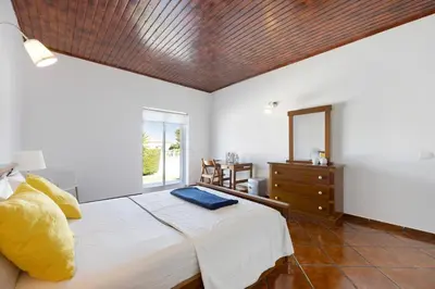 a bedroom with a white bed with a blue wall at Villa Oliveira in Aljezur